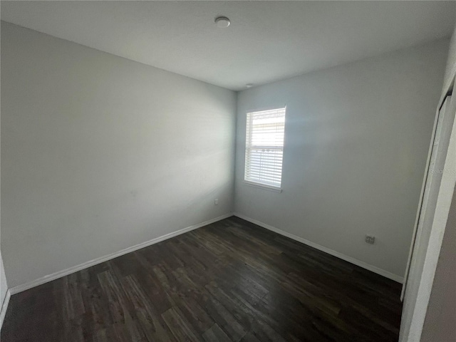 spare room featuring dark wood-style flooring and baseboards