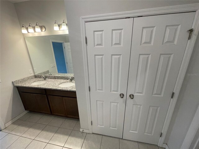 bathroom with tile patterned floors, baseboards, double vanity, and a sink