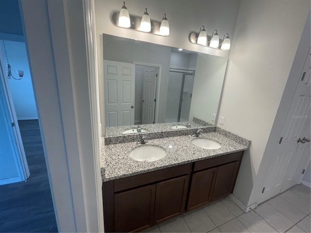 bathroom with double vanity, a sink, tile patterned floors, and baseboards