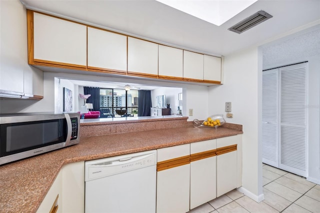 kitchen featuring visible vents, stainless steel microwave, light tile patterned floors, white cabinets, and dishwasher