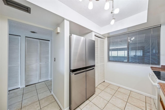 kitchen with baseboards, freestanding refrigerator, light tile patterned flooring, and visible vents