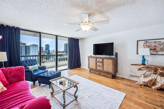 living area with baseboards, a textured ceiling, ceiling fan, and wood finished floors