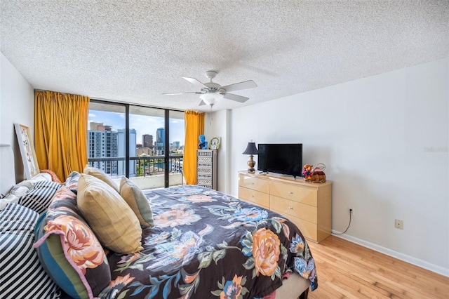 bedroom with baseboards, a ceiling fan, a textured ceiling, and light wood-style flooring