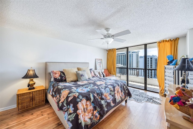 bedroom with expansive windows, a textured ceiling, wood finished floors, and access to exterior