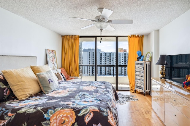 bedroom featuring expansive windows, a textured ceiling, light wood finished floors, and access to exterior