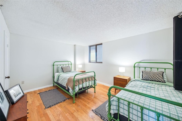 bedroom with baseboards, a textured ceiling, and wood finished floors