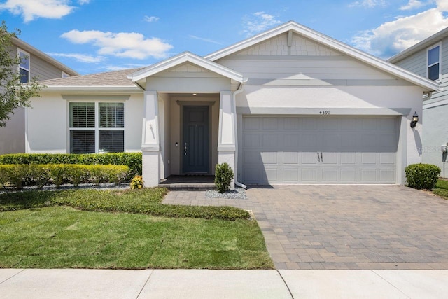 ranch-style home with a garage, stucco siding, decorative driveway, and a front yard
