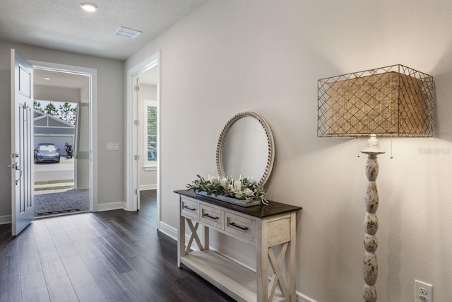 foyer entrance featuring baseboards, visible vents, and dark wood-style floors