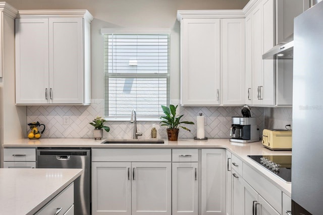 kitchen with appliances with stainless steel finishes, tasteful backsplash, a sink, light countertops, and white cabinets