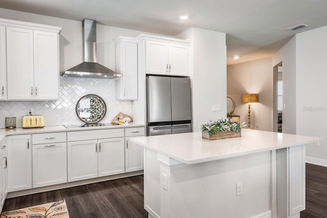 kitchen with visible vents, freestanding refrigerator, dark wood-style flooring, and wall chimney range hood