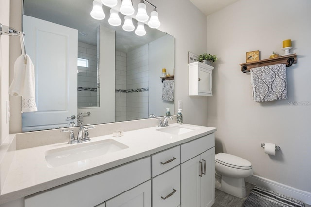 full bathroom with double vanity, a sink, baseboards, and toilet