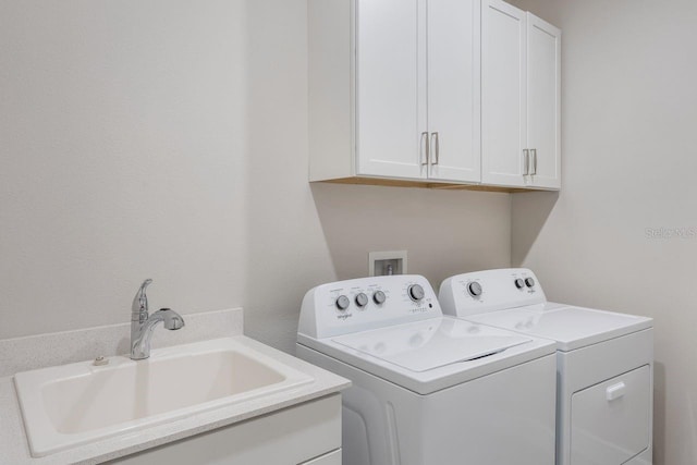clothes washing area featuring a sink, cabinet space, and washing machine and dryer