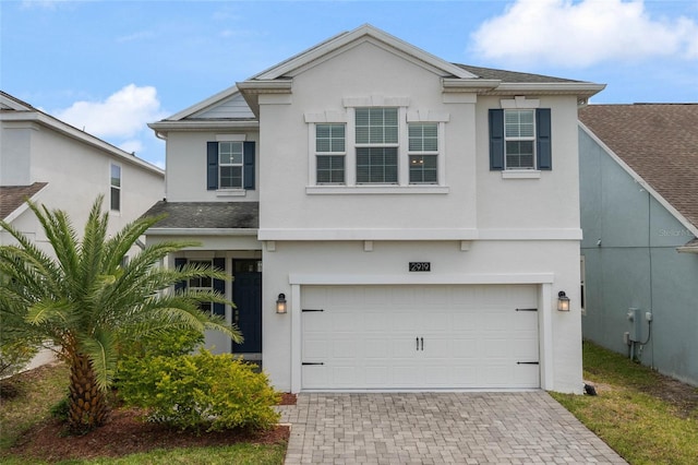 view of front of house with decorative driveway, a garage, stucco siding, and a shingled roof