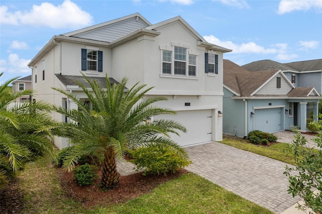 view of front of property featuring stucco siding, decorative driveway, and a garage