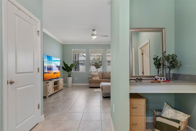 living area with baseboards, ceiling fan, and crown molding