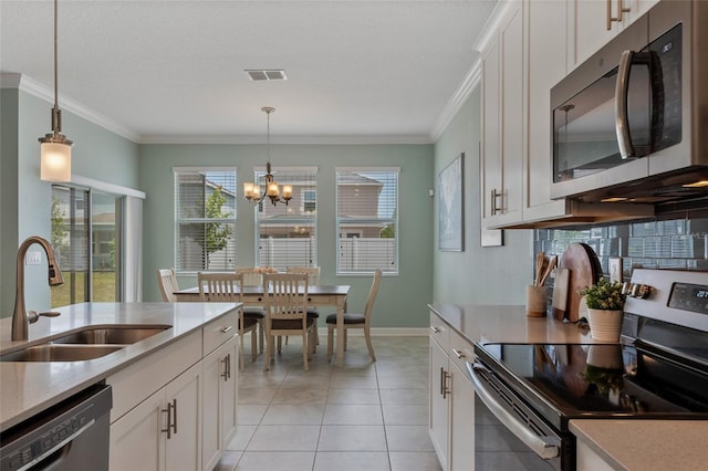 kitchen featuring a sink, light countertops, an inviting chandelier, dishwashing machine, and electric stove