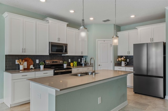 kitchen featuring a sink, decorative backsplash, a center island with sink, white cabinets, and appliances with stainless steel finishes