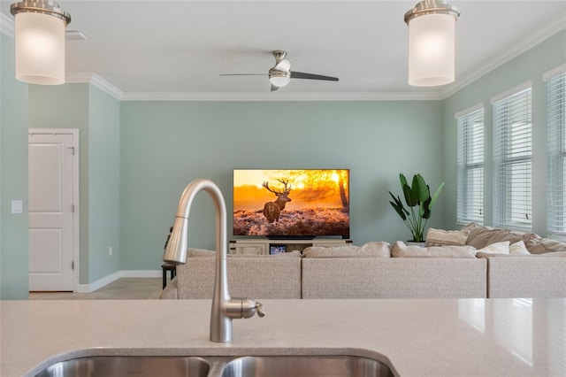 kitchen featuring light countertops, a ceiling fan, crown molding, and a sink