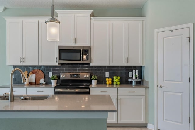 kitchen with tasteful backsplash, stainless steel appliances, white cabinets, and a sink