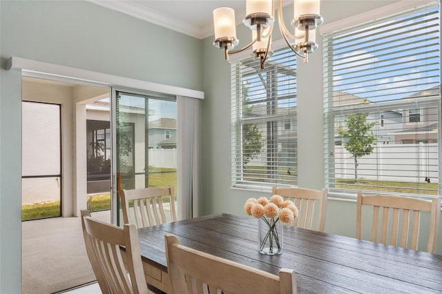 carpeted dining space with ornamental molding, a notable chandelier, and a wealth of natural light