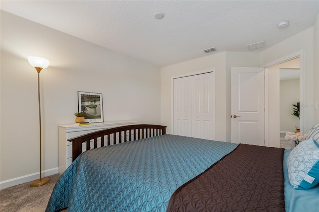 bedroom with a closet, carpet, baseboards, visible vents, and a textured ceiling