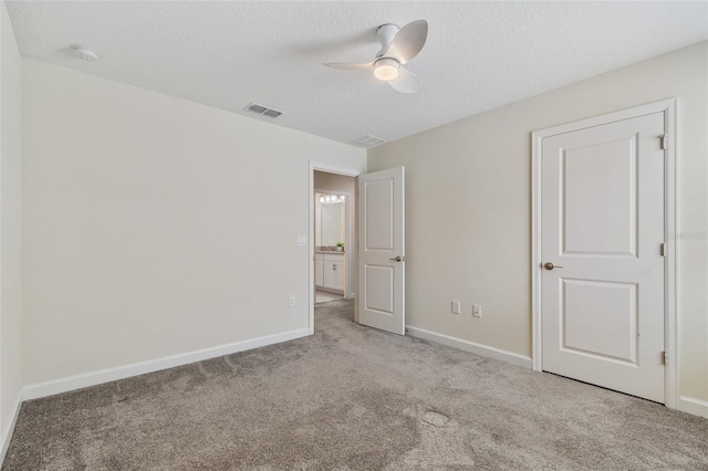 unfurnished bedroom featuring a textured ceiling, visible vents, carpet floors, and baseboards