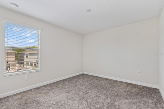 carpeted spare room featuring baseboards