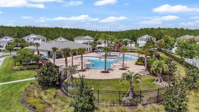 pool featuring a patio, a residential view, a lawn, a view of trees, and a fenced backyard