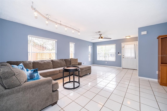 living area with light tile patterned floors, ceiling fan, visible vents, and baseboards