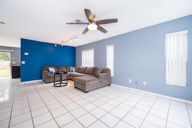 living area featuring light tile patterned floors, a ceiling fan, rail lighting, and baseboards