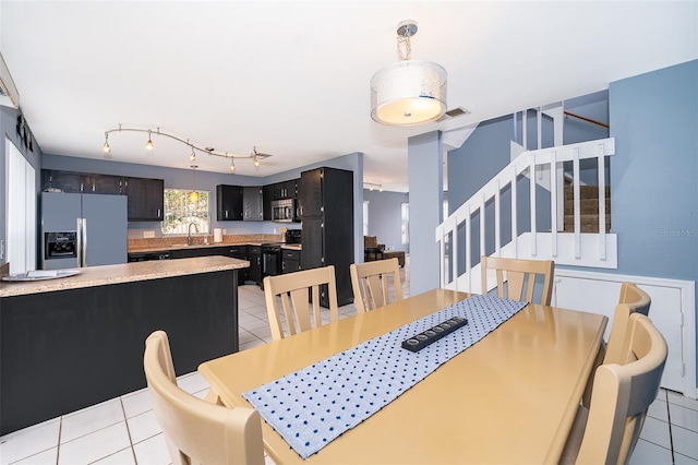 dining area with rail lighting, light tile patterned flooring, visible vents, and stairway
