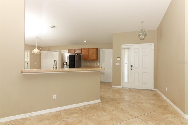 212 Regency St, Davenport, FL 33896 - kitchen with visible vents, hanging light fixtures, brown cabinets, light countertops, and stainless steel fridge
