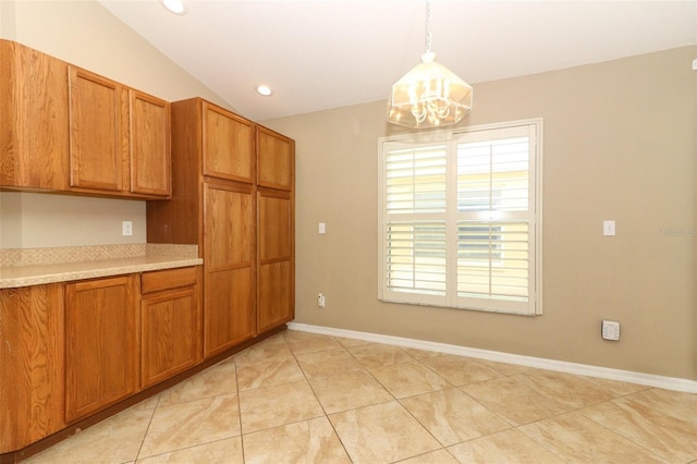 212 Regency St, Davenport, FL 33896 - kitchen featuring brown cabinets, light countertops, light tile patterned floors, lofted ceiling, and an inviting chandelier