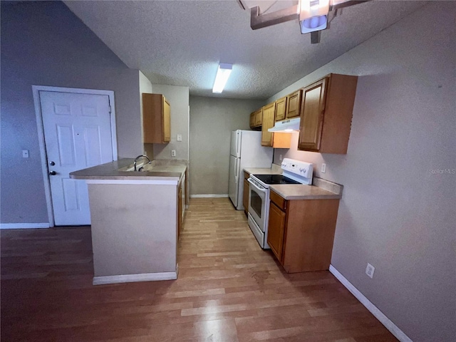 kitchen featuring a textured ceiling, light wood-type flooring, baseboards, under cabinet range hood, and white appliances