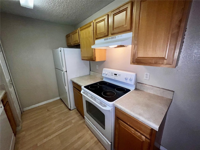 kitchen with light countertops, a textured ceiling, under cabinet range hood, and white appliances