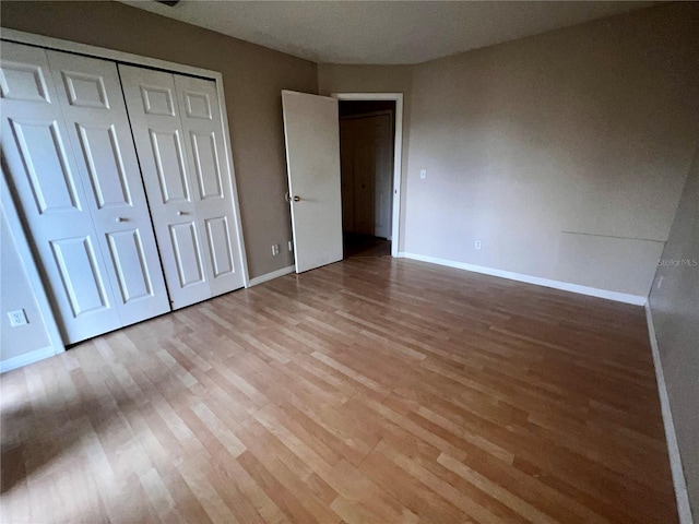 unfurnished bedroom featuring a closet, baseboards, and light wood-type flooring