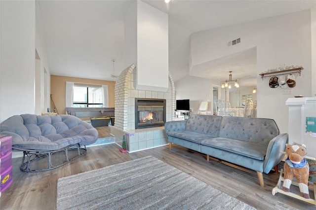 516 Fort Smith Blvd, Deltona, FL 32738 - living area featuring a tile fireplace, wood finished floors, a ceiling fan, a chandelier, and high vaulted ceiling
