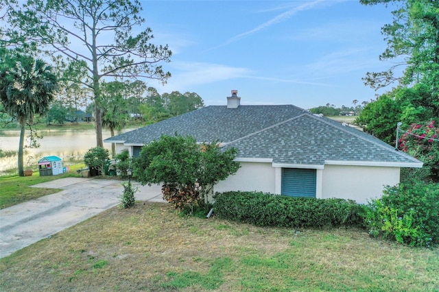 516 Fort Smith Blvd, Deltona, FL 32738 - view of side of home featuring a shingled roof, stucco siding, a chimney, concrete driveway, and a lawn