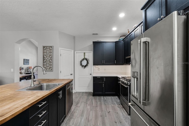 4027 Lakeside Reserve Ct, Orlando, FL 32810 - kitchen with wood counters, appliances with stainless steel finishes, a sink, and dark cabinetry