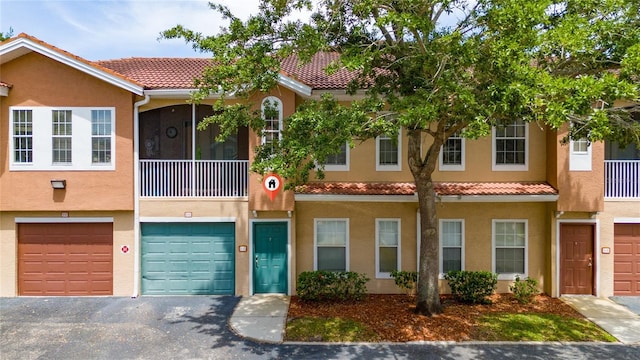 multi unit property featuring a tile roof, driveway, a garage, and stucco siding