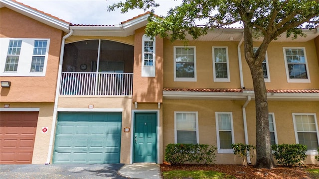multi unit property with a garage, stucco siding, and a tile roof