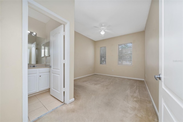 unfurnished bedroom with baseboards, connected bathroom, light colored carpet, and a sink