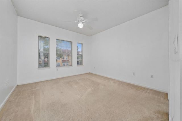 empty room with baseboards, light carpet, and ceiling fan