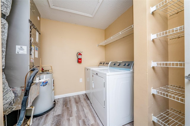 laundry area featuring washing machine and clothes dryer, light wood-style flooring, water heater, attic access, and heating unit