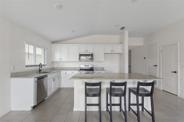 3222 Sweet Acres Pl, Saint Cloud, FL 34772 - kitchen with a kitchen island, appliances with stainless steel finishes, vaulted ceiling, a sink, and a breakfast bar