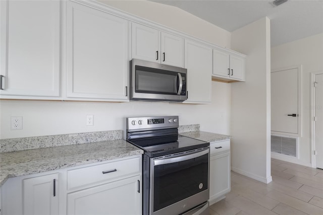 3222 Sweet Acres Pl, Saint Cloud, FL 34772 - kitchen with visible vents, appliances with stainless steel finishes, baseboards, white cabinets, and light stone counters
