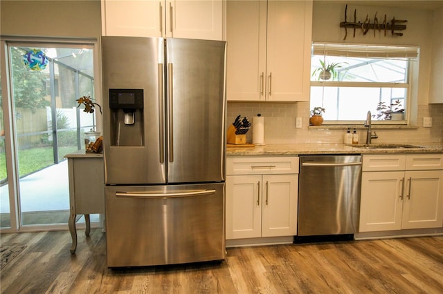 1529 Glastonberry Rd, Maitland, FL 32751 - kitchen featuring appliances with stainless steel finishes, a sink, wood finished floors, light stone countertops, and tasteful backsplash