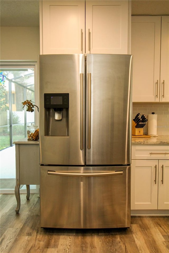 1529 Glastonberry Rd, Maitland, FL 32751 - kitchen view of stainless steel fridge with ice dispenser, light wood-type flooring, white cabinets, and decorative backsplash