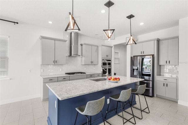 kitchen featuring backsplash, a kitchen bar, decorative light fixtures, appliances with stainless steel finishes, and wall chimney exhaust hood