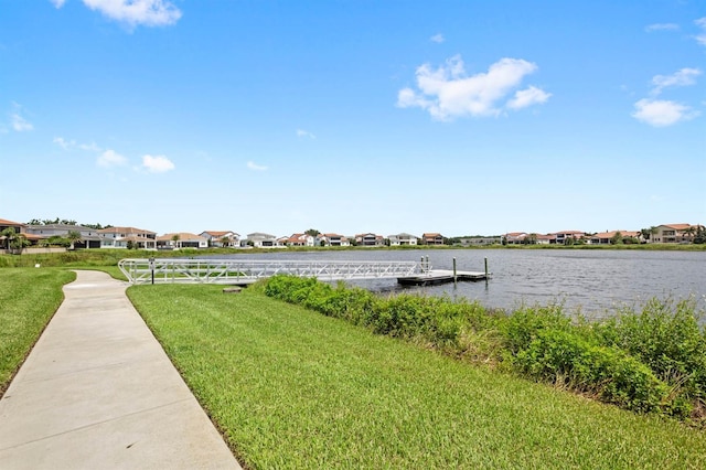 view of dock featuring a water view, a yard, and a residential view